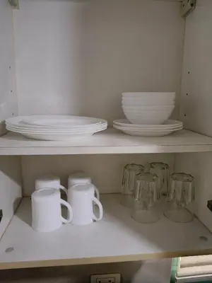 a shelf with plates and cups and dishes on it at LDN Secret 1BR across NAIA Terminal 3 in Manila