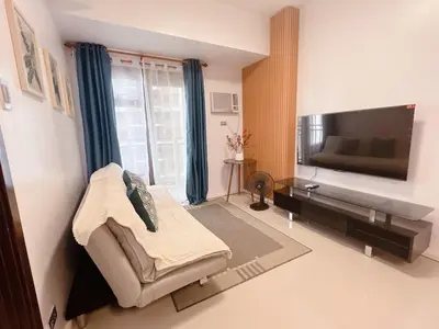 a living room with a couch and a flat screen tv at Modern condo near US Embassy in Manila
