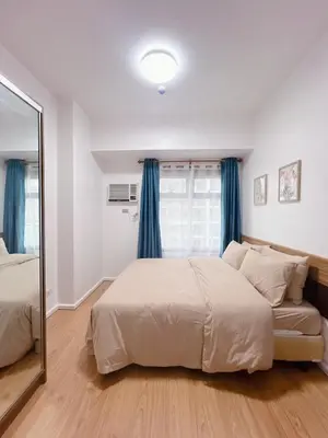 a bedroom with a large bed and a mirror at Modern condo near US Embassy in Manila