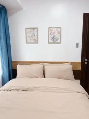 a bed with white sheets and two pictures on the wall at Modern condo near US Embassy in Manila