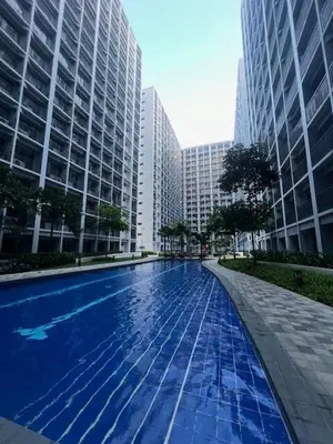 a large swimming pool in a city with tall buildings at Wander & Chill Staycation in Manila