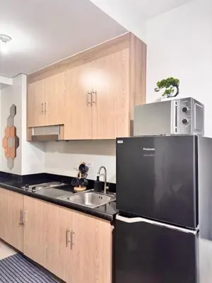 a kitchen with a black refrigerator and wooden cabinets at Wander & Chill Staycation in Manila