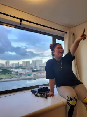 a woman sitting on a window sill with her arm up at Barkada Pamilya BnB by Metro Staycation in Manila