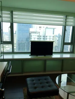 a desk with a monitor in a room with a window at Alphaland Suites Apartment Hotel in Manila