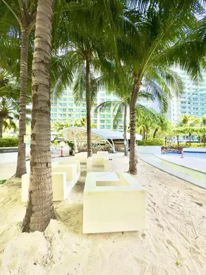 a row of benches on a beach with palm trees at Azure Resort Residence, 1bedroom with balcony Beach view in Manila