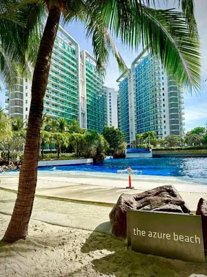 a sign on a beach with a palm tree and buildings at Azure Resort Residence, 1bedroom with balcony Beach view in Manila