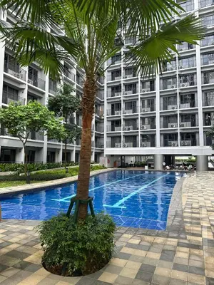 a palm tree in front of a large building at One Bedroom Apartment near MOA in Manila