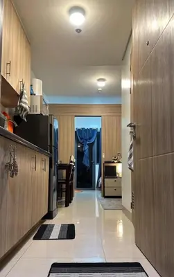 a large kitchen with wooden cabinets and a hallway at Shore 2 Residence in Manila