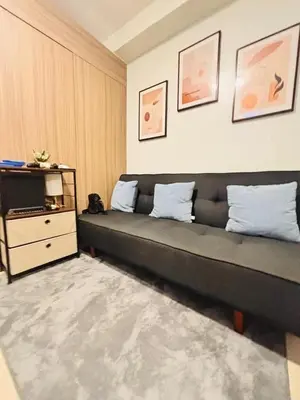 a living room with a black couch and a dresser at Shore 2 Residence in Manila