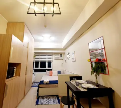 a small room with a bed and a dining table at Pixie Dust Suite in Manila