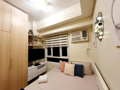 a small bedroom with a bed and a window at Pixie Dust Suite in Manila