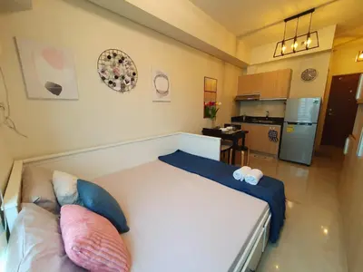 a bedroom with a large bed and a kitchen at Pixie Dust Suite in Manila