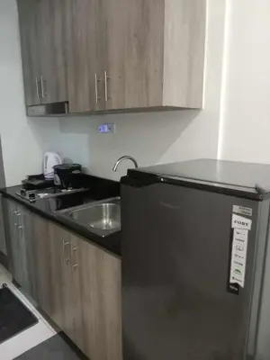 a kitchen with a sink and a black refrigerator at FAME Bedroom in Manila