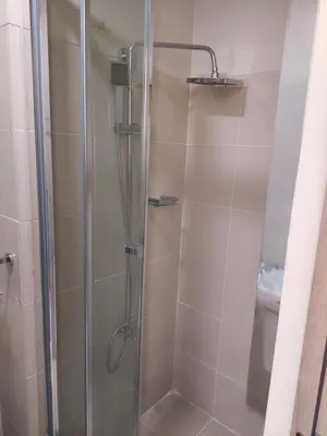 a shower with a glass door in a bathroom at FAME Bedroom in Manila