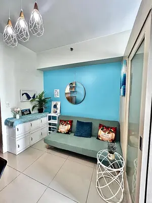 a living room with a couch and a blue wall at Jazz Residences Makati Tower B in Manila