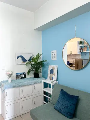 a living room with a blue wall and a mirror at Jazz Residences Makati Tower B in Manila