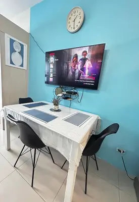a table with chairs and a clock on a wall at Jazz Residences Makati Tower B in Manila