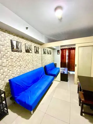 a blue couch in a living room with a table at Sea residences by mavis in Manila
