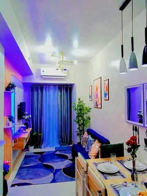 a living room with a table and a blue rug at Dream City Staycation -Shore3 Residences Tower 2 in Manila