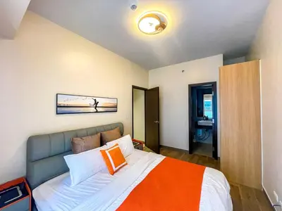 a bedroom with a bed with an orange and white blanket at Cozy 3BR near Airport & Okada, Solaire II Infinity Pool in Manila