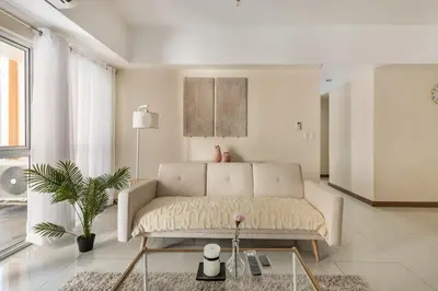a white living room with a couch and a table at Minimalist Haven 3BR unit at Mckinley Hill in Manila