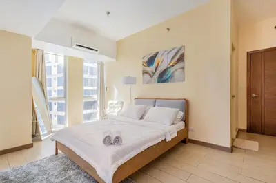 a bedroom with a bed with two towels on it at Minimalist Haven 3BR unit at Mckinley Hill in Manila