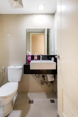 a bathroom with a toilet and a sink and a mirror at Minimalist Haven 3BR unit at Mckinley Hill in Manila