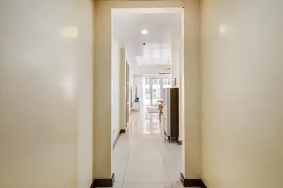 a hallway with white walls and a white tile floor at Minimalist Haven 3BR unit at Mckinley Hill in Manila