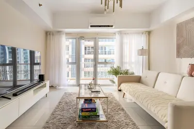 a living room with a couch and a tv at Minimalist Haven 3BR unit at Mckinley Hill in Manila