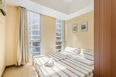 a bedroom with a bed and a large window at Minimalist Haven 3BR unit at Mckinley Hill in Manila