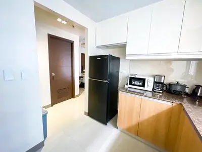 a kitchen with a black refrigerator and white cabinets at Cozy 2BR Suite near Airport & Okada, Infinity Pool in Manila
