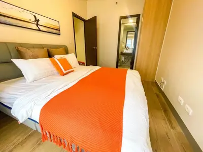 an orange and white bed in a room at Spacious 1BR Suite near Okada, Solaire, Airport in Manila