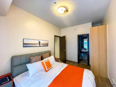 a bedroom with a bed with an orange and white blanket at Spacious 1BR Suite near Okada, Solaire, Airport in Manila