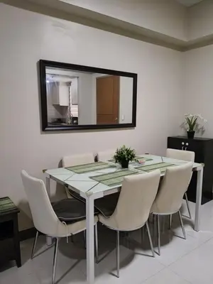 a dining room with a table and chairs and a mirror at LDN Two Palm Tree Villa LFamilia in Manila