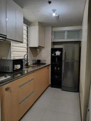 a kitchen with wooden cabinets and a stainless steel refrigerator at LDN Two Palm Tree Villa LFamilia in Manila