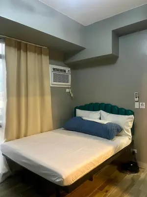 a bed with a green headboard in a room at 1 BR Executive Suite Gentry Manor by JMS in Manila