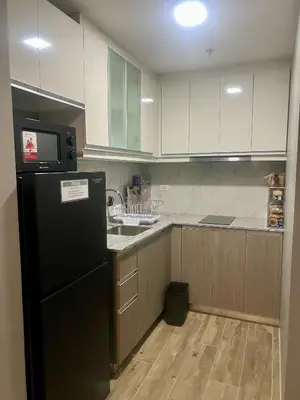 a kitchen with a black refrigerator and wooden cabinets at 1 BR Executive Suite Gentry Manor by JMS in Manila