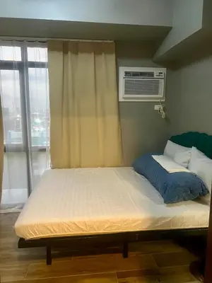 a large bed in a room with a window at 1 BR Executive Suite Gentry Manor by JMS in Manila