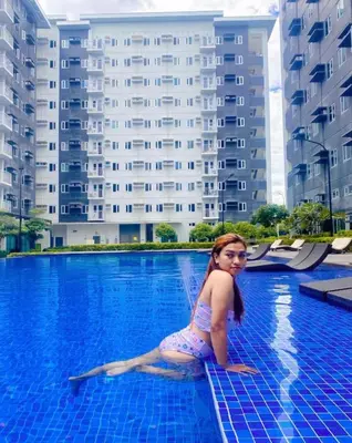 a young girl is sitting in a swimming pool at Charm Residences Building E in Manila