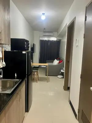 a kitchen with a black refrigerator and a living room at 1 Br Family Suite in S Residences by JMS in Manila