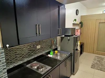 a kitchen with black cabinets and a sink and a refrigerator at Shore Residences MOA Minimalist Room in Manila