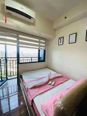 a bedroom with a bed with pink sheets and a television at Stylish Condo in Makati City with stunning views in Manila