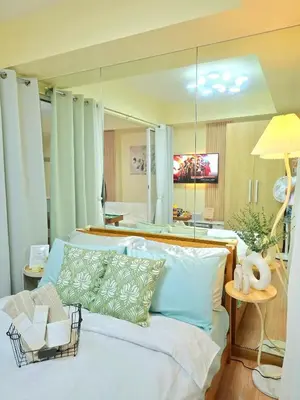 a bedroom with a white bed with a mirror at Azure Condotel and Resort in the City in Manila