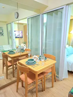 a dining room with two wooden tables and chairs at Azure Condotel and Resort in the City in Manila