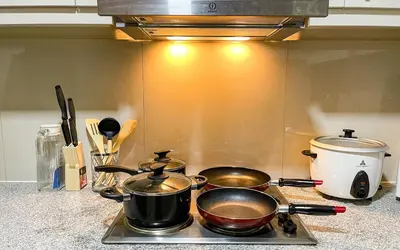 three pots and pans sitting on a stove in a kitchen at Cozy 2BR Suite in Uptown BGC with PS4 and walking distance to Malls and Restaurants in Manila