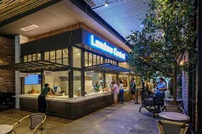 a group of people standing around a food counter in a building at Cozy 2BR Suite in Uptown BGC with PS4 and walking distance to Malls and Restaurants in Manila