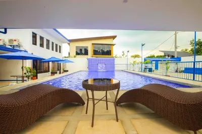a swimming pool with a table and chairs in front of a house at Private Resort in upper Antipolo in Antipolo