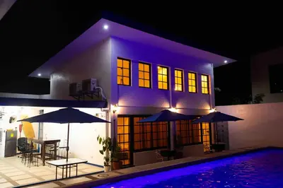 a house with a pool and umbrellas in front of it at Private Resort in upper Antipolo in Antipolo