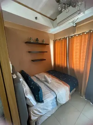 a small bed in a room with orange curtains at 1528 pool view with balcony in Manila