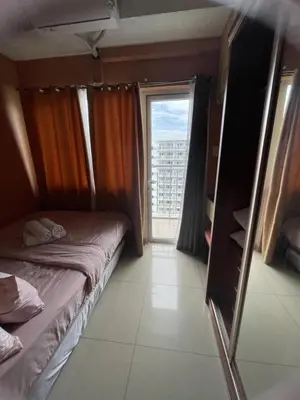 a bedroom with a bed and a large window at 1528 pool view with balcony in Manila